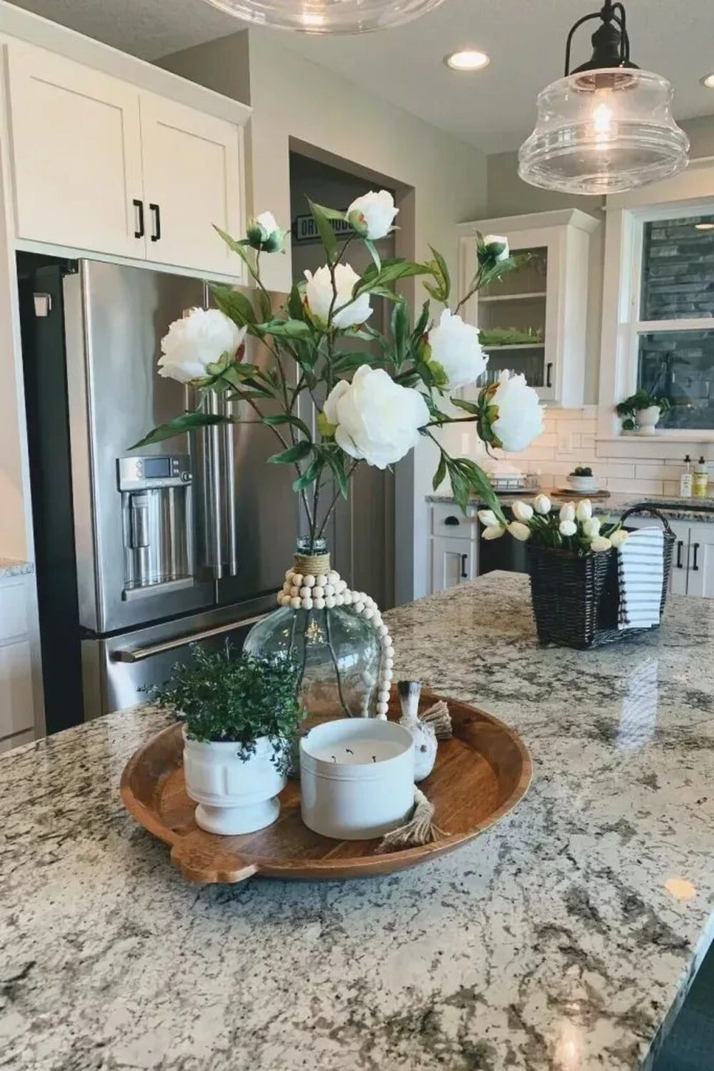a wood tray with green plant and white flower on kitchen island