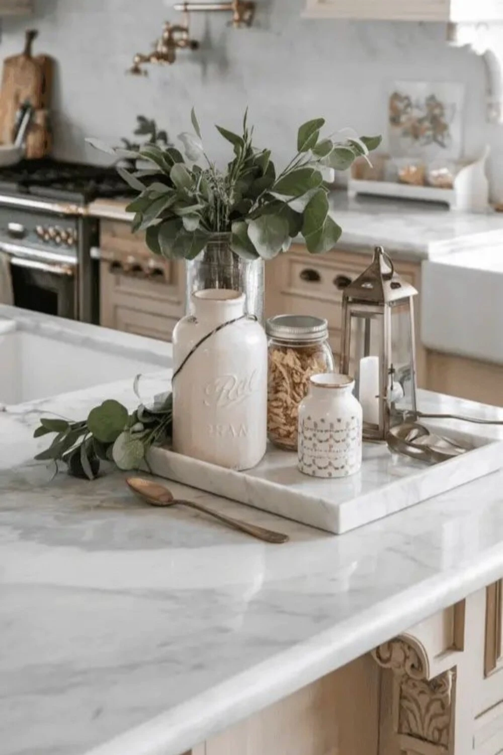 a marble tray with vase, bottle, and candle on kitchen island