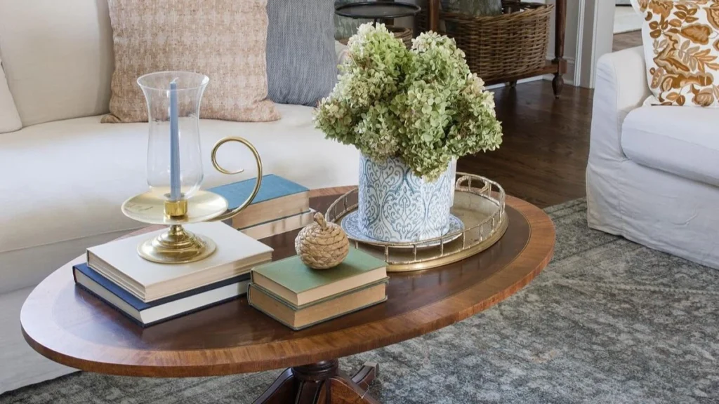 an oval coffee table decorated with books, plant and tray