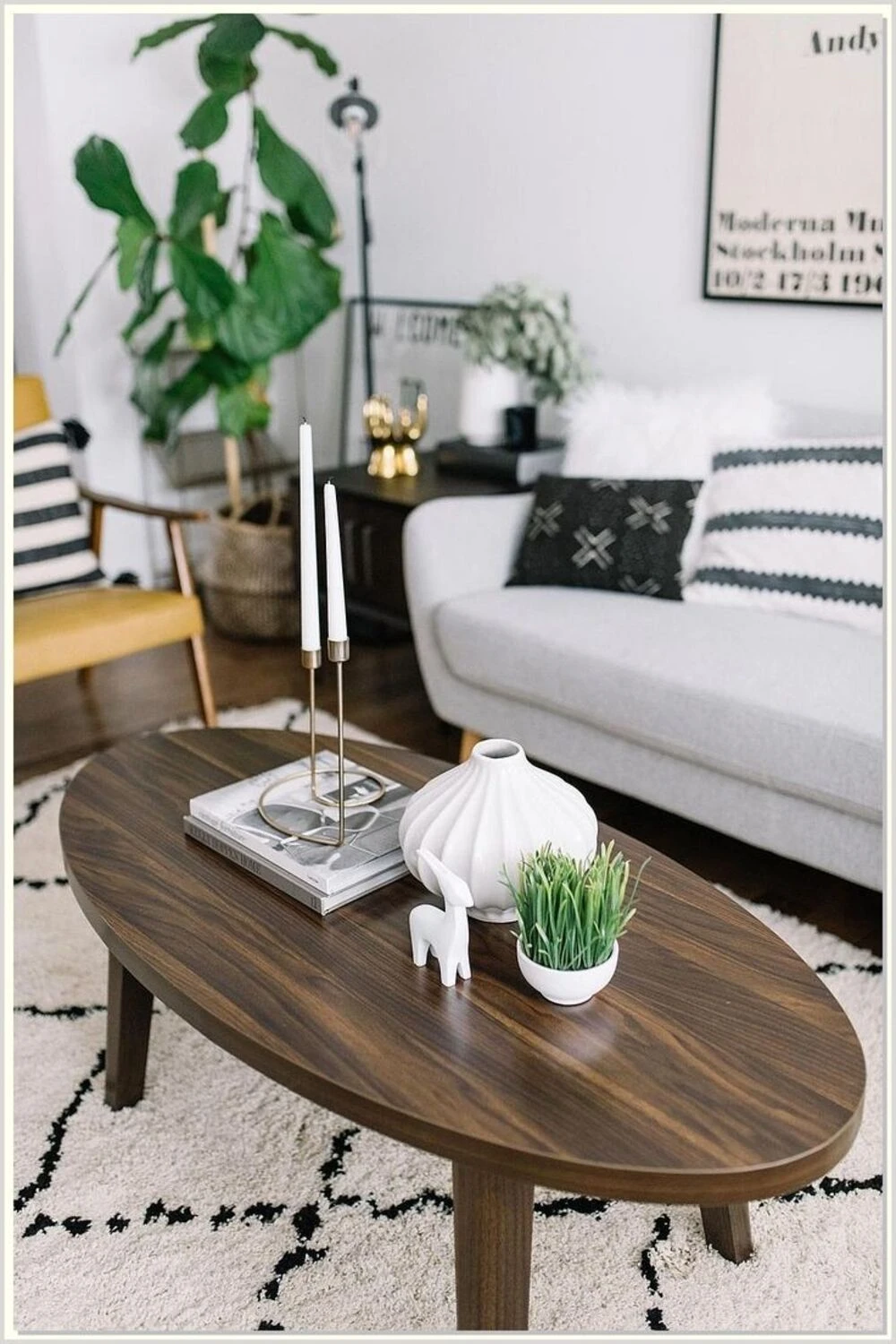 an oval coffee table with candles and vase