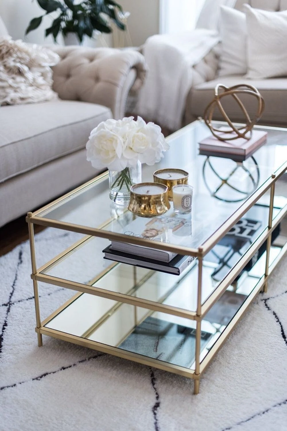 a rectangle glass coffee table in simple style with a bottle of flower, candles, and an art object