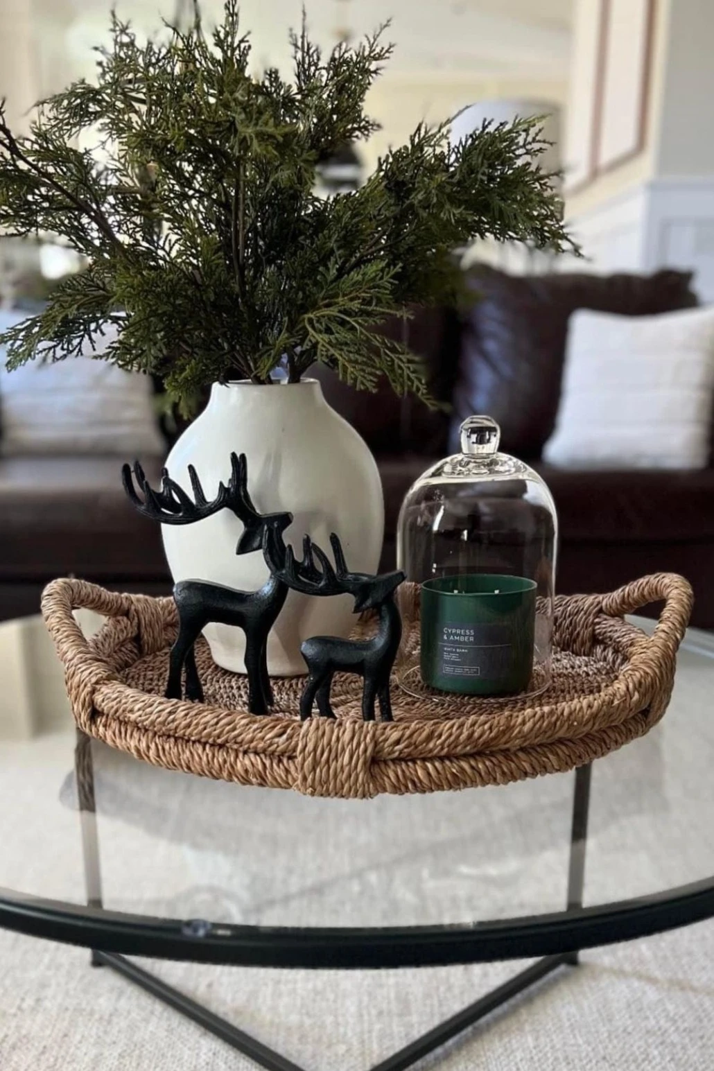 a round glass coffee table with a vase of mistletoe and reindeer figures