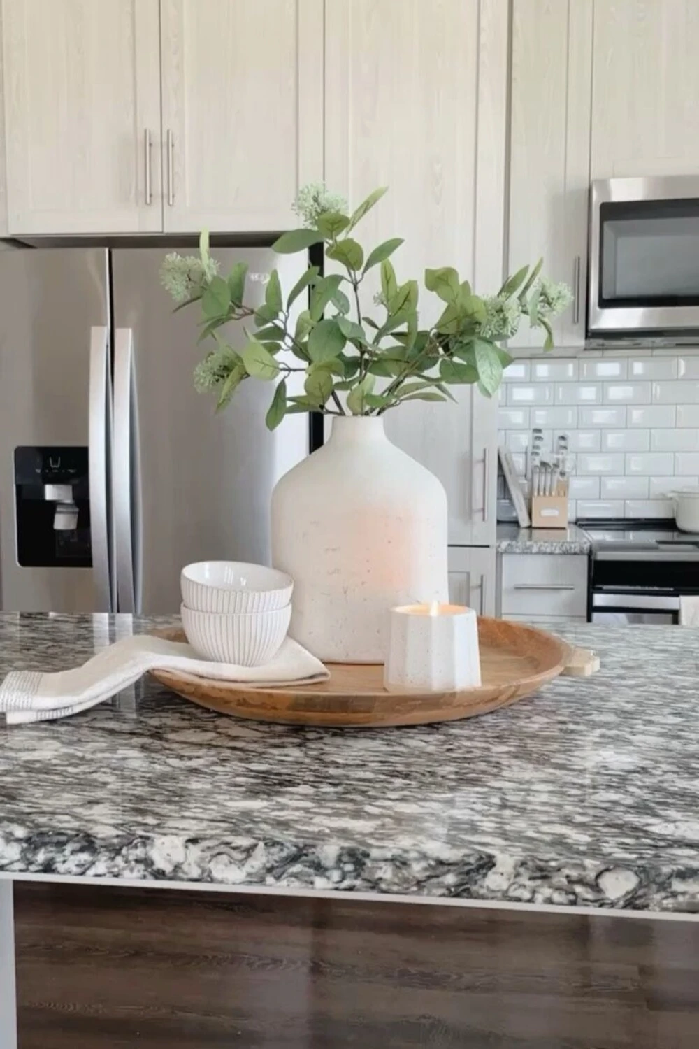 a kitchen island countertop decorated with big vase, bowl, and candle