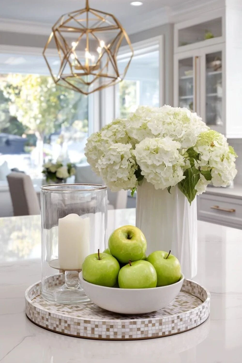 a kitchen island countertop decorated with a bowl of fruit, flowers, and candle