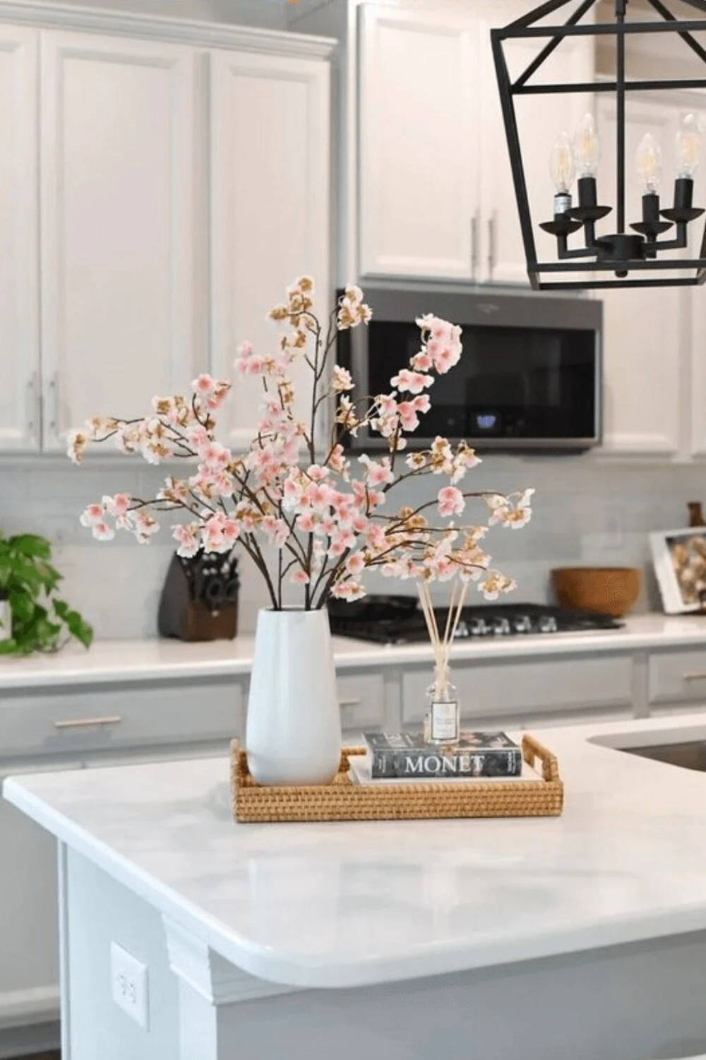 a kitchen island countertop decorated with flower in vase, scent, and books